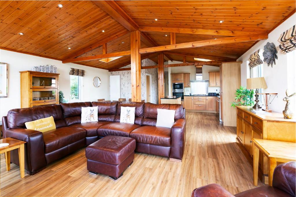 Una sala de estar con muebles de cuero marrón y techos de madera. en Immaculate 3-Bedroom Private Lodge near York, en York