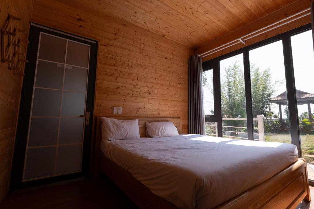 a bedroom with a bed with a glass door at Homestay Đồi Mây Lộc Tân Bảo Lộc in Bảo Lâm