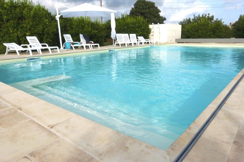 a large swimming pool with chairs and an umbrella at L'Antico Trappeto in Noto