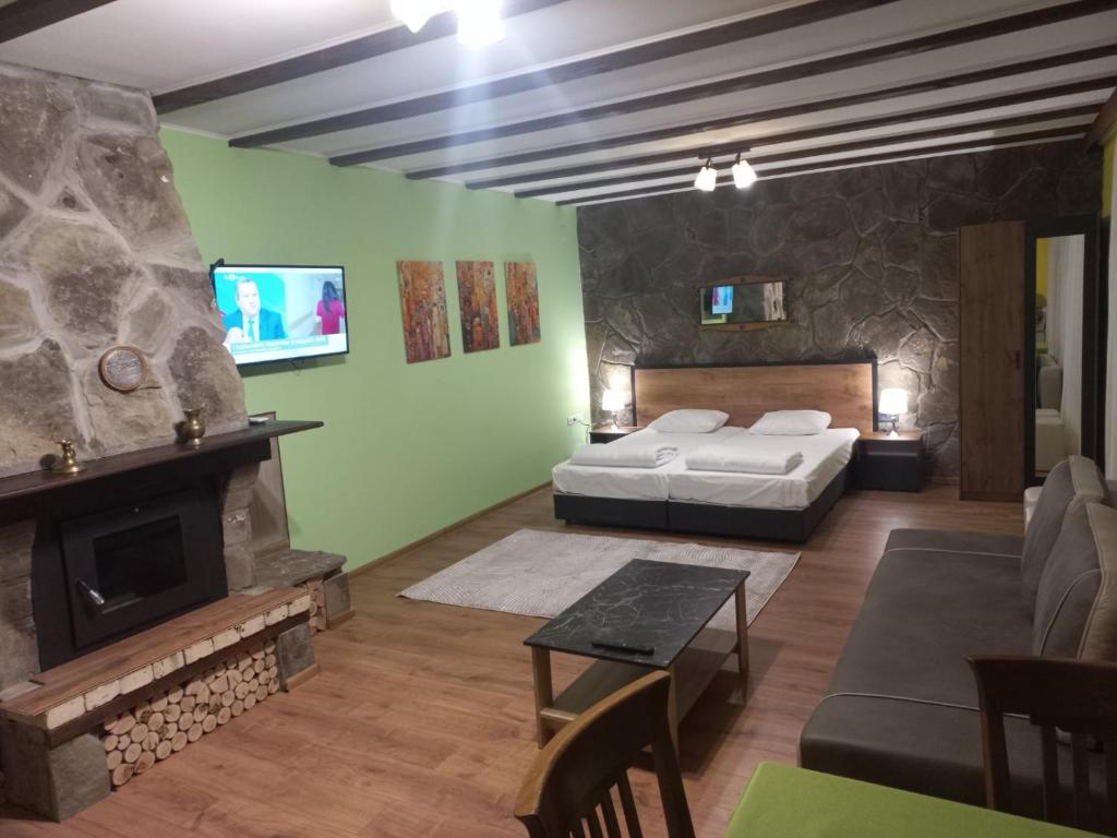 een woonkamer met een bed en een open haard bij стаи за гости TODA in Troyan