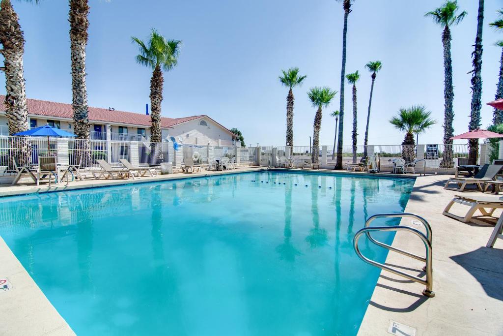 a large swimming pool with palm trees and chairs at Motel 6-Eloy, AZ - Casa Grande in Eloy