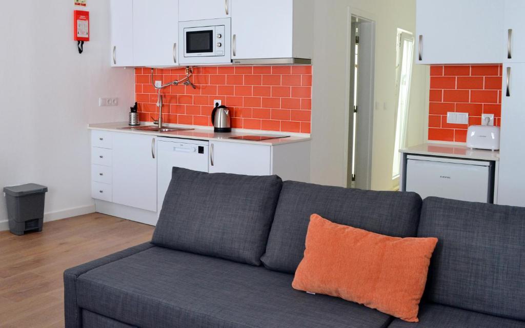 ein graues Sofa mit einem orangefarbenen Kissen in einer Küche in der Unterkunft Casa João de Quintal in Elvas