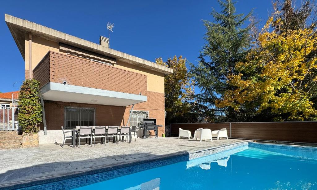 a swimming pool with chairs and a building at Casa Abetos in Collado Mediano