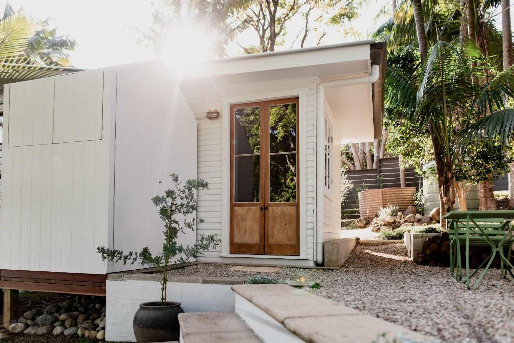 a small white house with a wooden door at Romantic Escape l Firepit & Views l Nova Escapes in Goonengerry