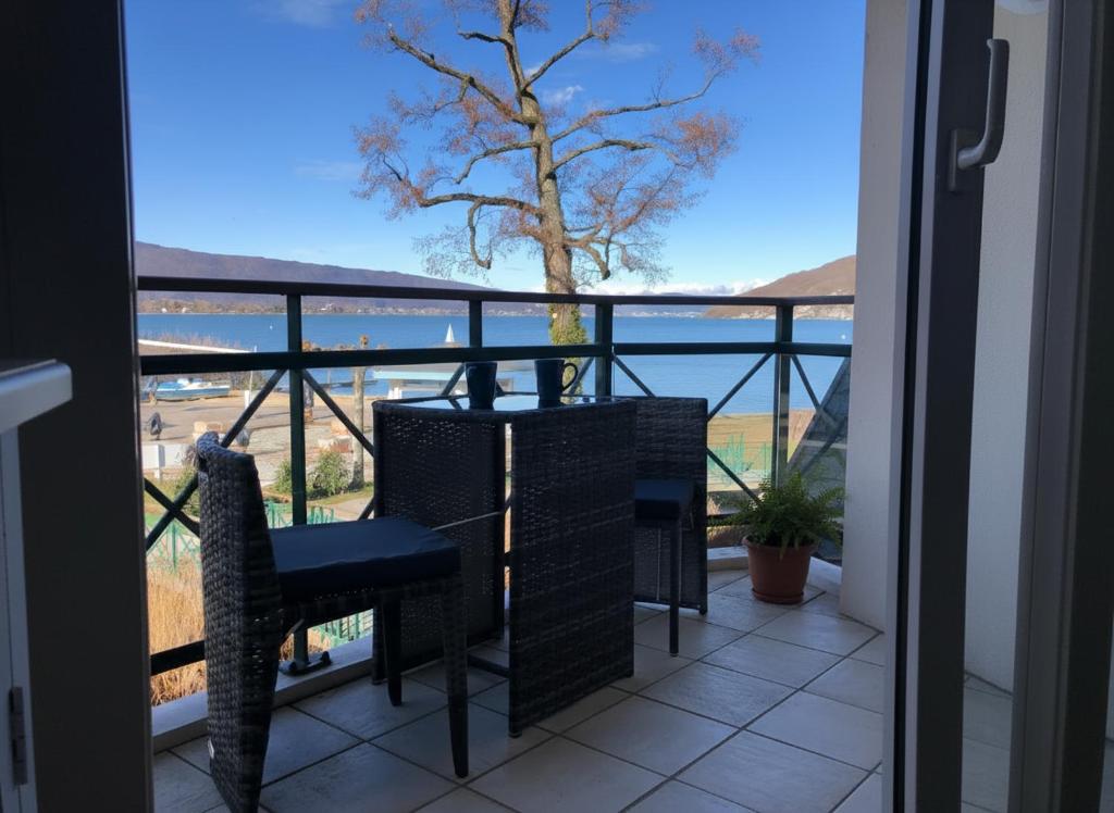 a balcony with a table and chairs and a view of the ocean at Studio Vue sur le Lac d'Annecy Plage et Parking Privés in Duingt