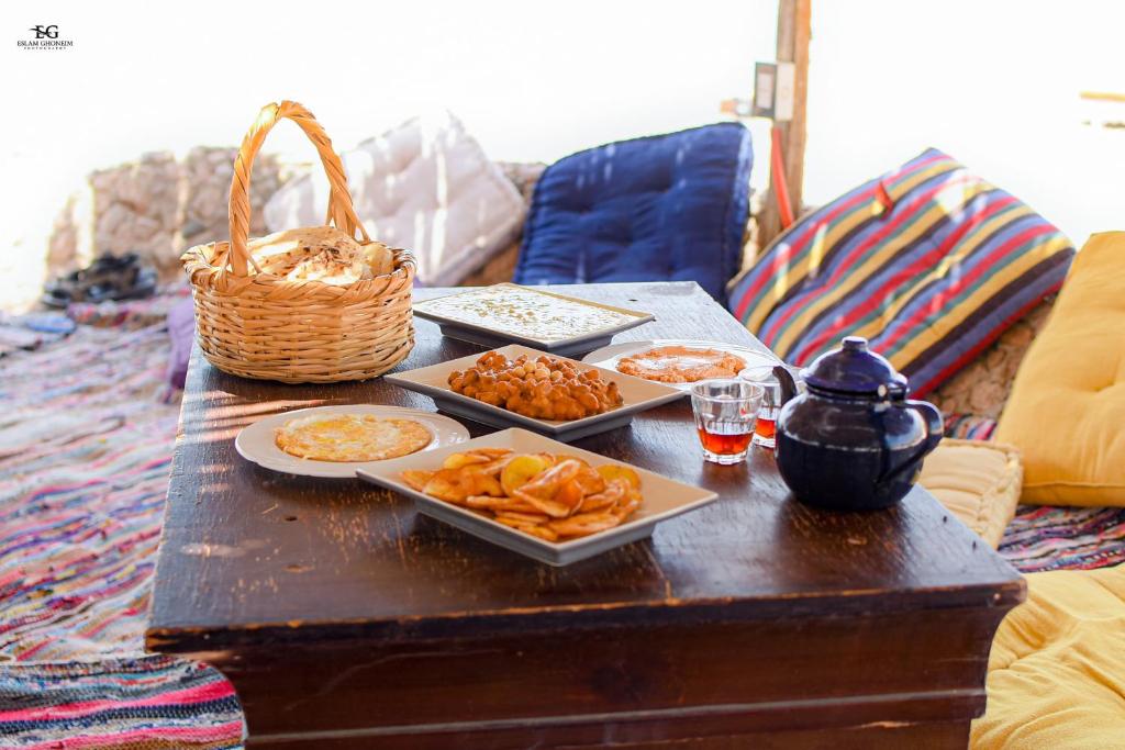 une table avec des assiettes de nourriture et un panier dessus dans l'établissement Palm Valley camp, à Nuweiba‘ el Muzeinah