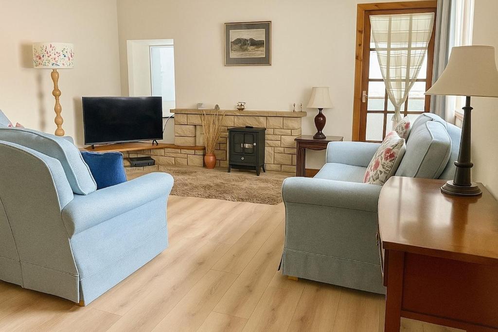 een woonkamer met twee stoelen en een televisie bij Beachy Days and Family Stays in Nairn