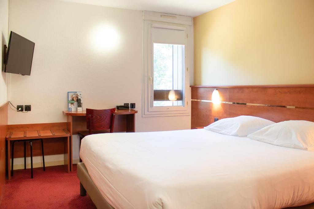 a bedroom with a large white bed and a window at Brit Hotel Agen - L'Aquitaine in Le Passage
