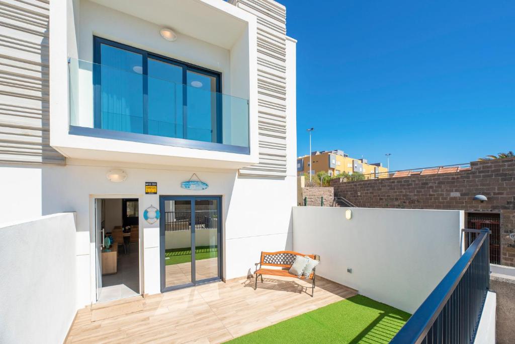 een wit huis met een bankje op een balkon bij MEDANO4YOU The Surf Backyard in El Médano
