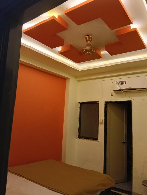 a room with a ceiling with an orange wall at Sahara yatri niwas in Kolhapur
