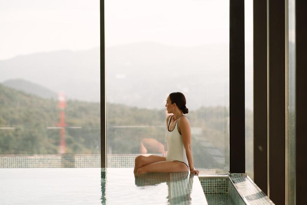 una mujer sentada en el borde de una piscina en The Vinea Collection Hotel by Piamonte Hotels, en Monção