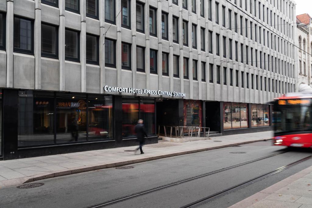 Un hombre caminando por una calle frente a un edificio. en Comfort Hotel Xpress Central Station, en Oslo