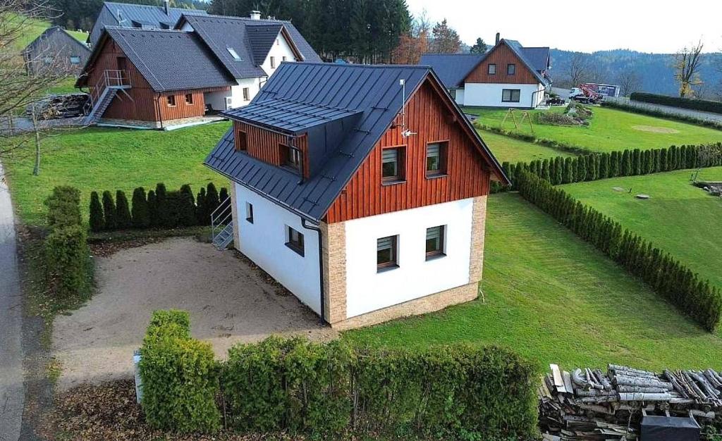 a small house with a red roof on a field at Apartmány Pelc in Kořenov