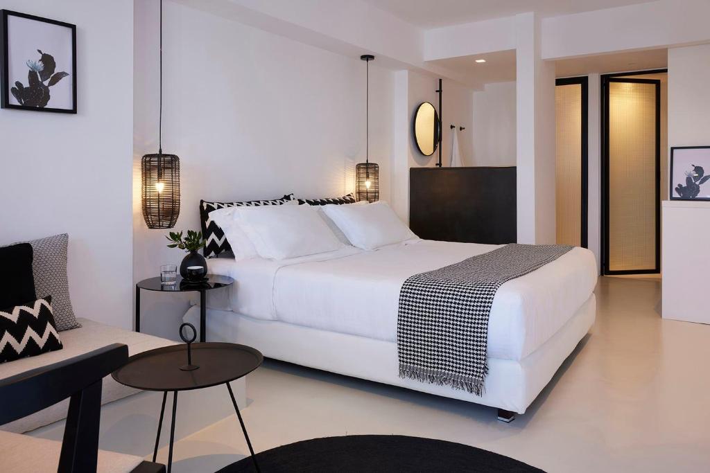 a bedroom with a large white bed and a couch at Hotiday Mykonos Agios Stefanos in Agios Stefanos