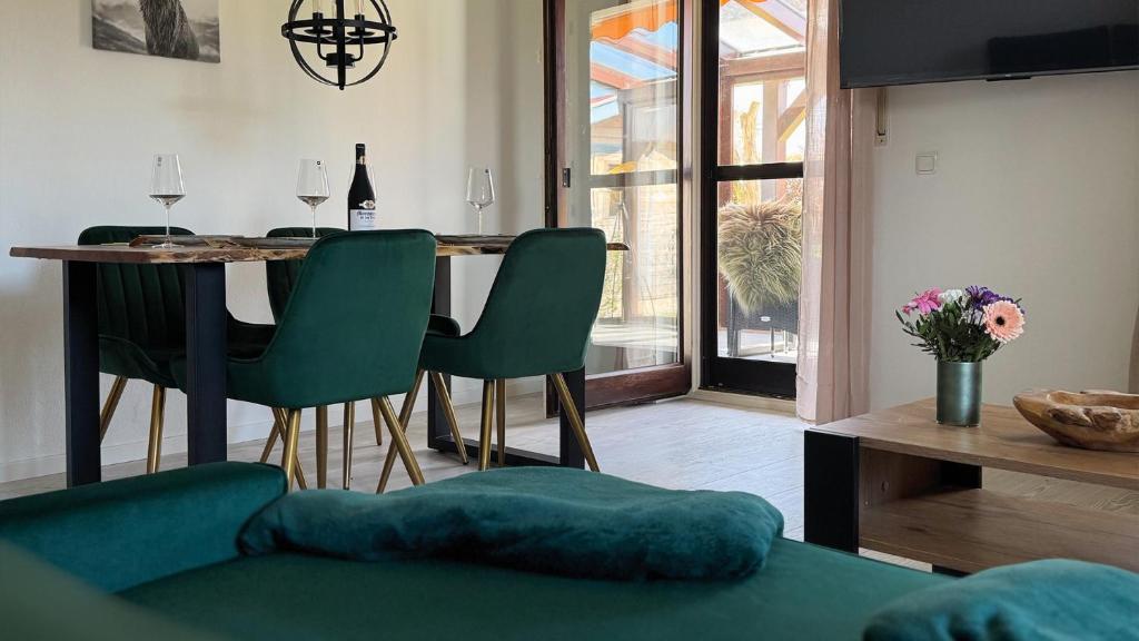 ein Wohnzimmer mit einem Tisch und grünen Stühlen in der Unterkunft Alpendomizil Haberspitz in Marquartstein