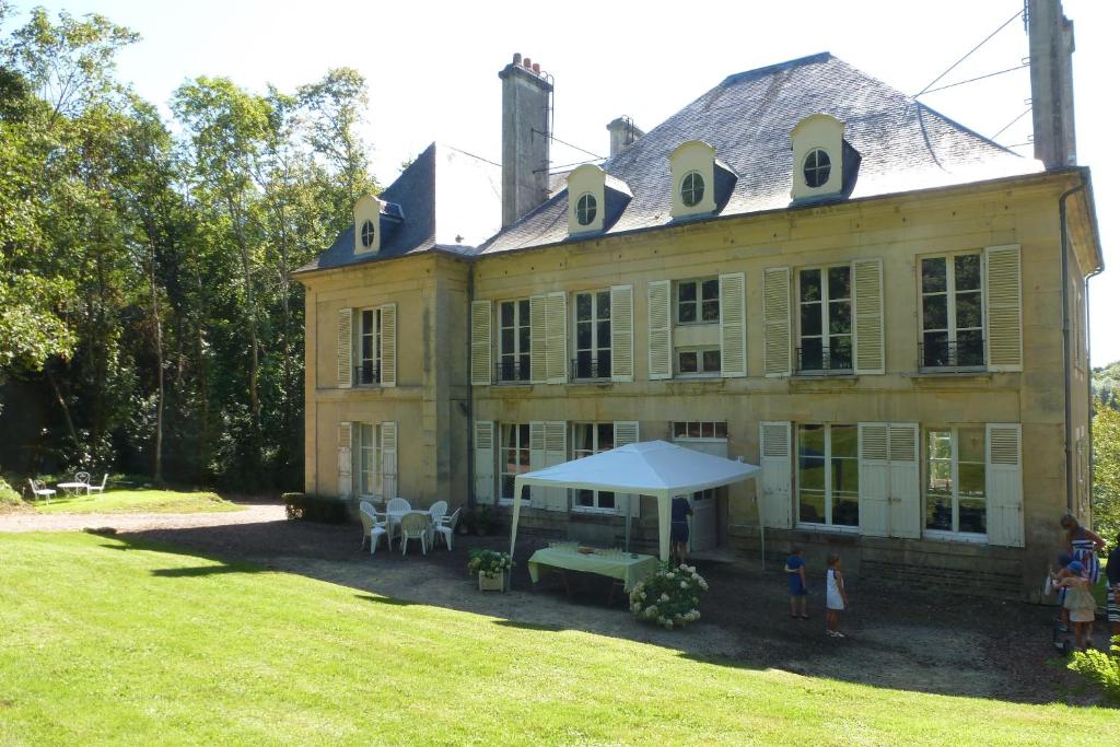 a large yellow house with a tent in the yard at Le Gîte du Bas Manoir in Bretteville-sur-Odon