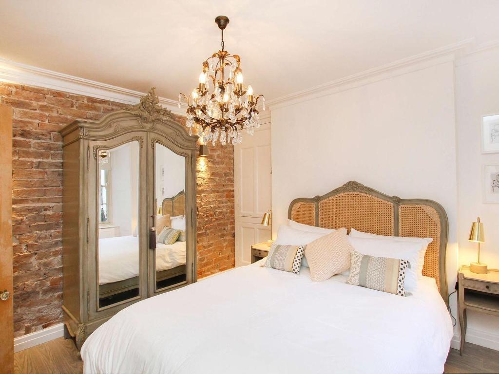 a bedroom with a large bed and a chandelier at Tri Raglan Bach in Beaumaris