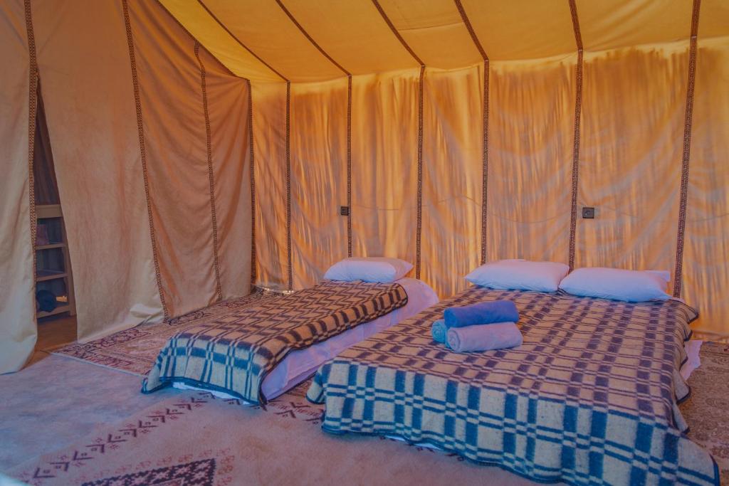 two beds sitting inside of a tent at Silent Camp in Mhamid