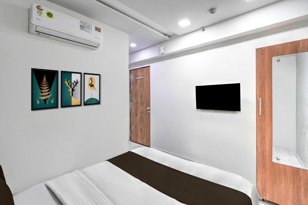 Zimmer mit einem Bett und einem TV in der Unterkunft Super Hotel O Sneh Rashmi Botanical Garden Surat Formerly Stadium Plaza in Bhatha