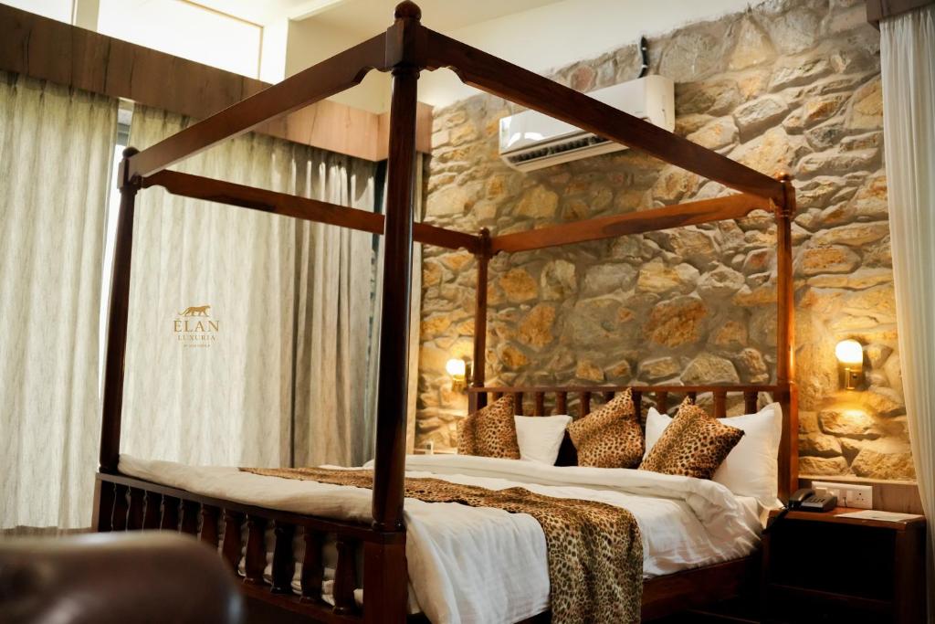 een slaapkamer met een hemelbed en een stenen muur bij Elan Luxuria Jawai in Bijāpur