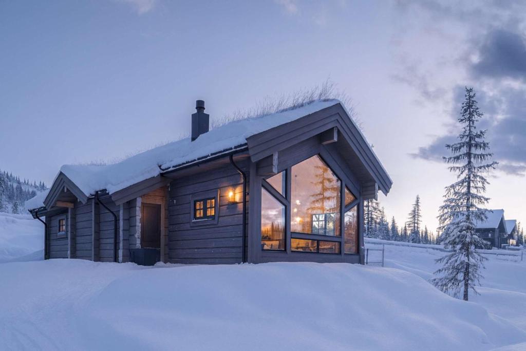 a log cabin in the snow with snow at Skjonnhet Cottage - Luxury Ski-in & ski-out chalet in Kvitfjell