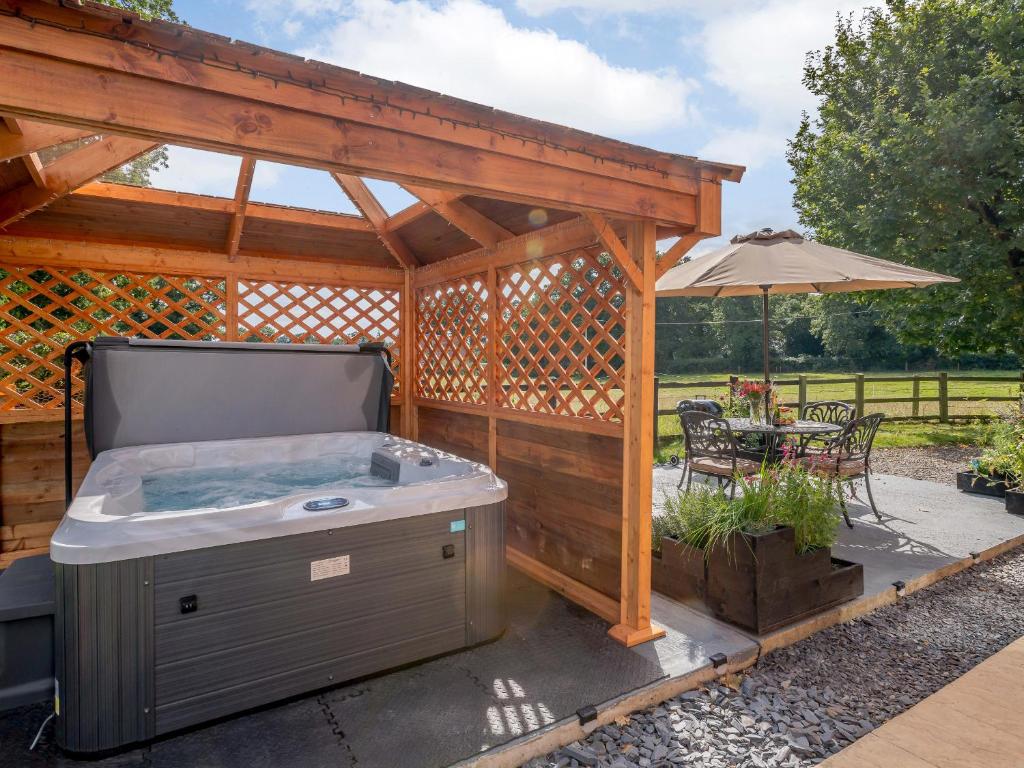 a hot tub in a pavilion with a table and an umbrella at Paddock End in Great Plumstead