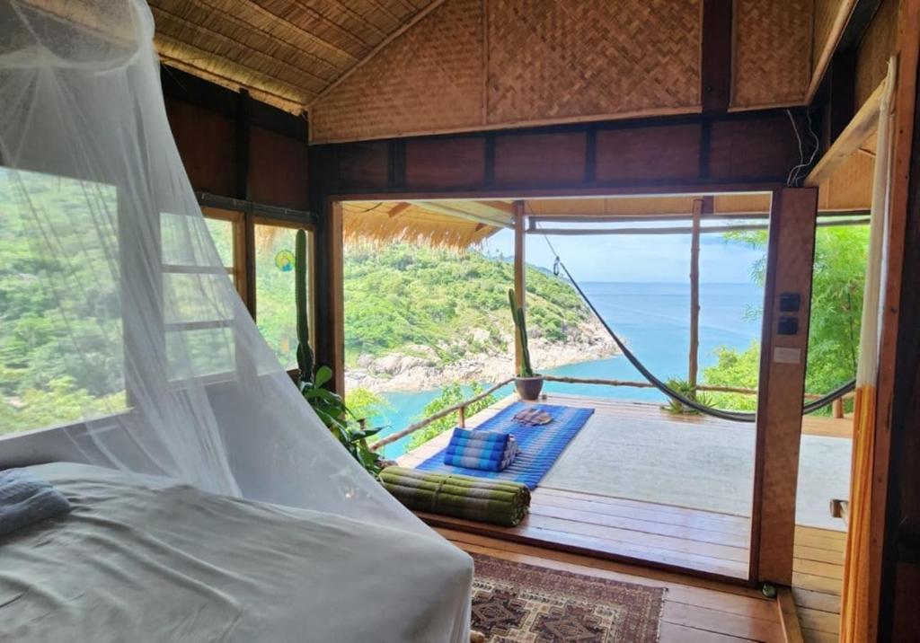 a bed in a room with a view of the ocean at Why Nam Stunning Beach & Ocean View Jungle Penthouse in Ko Phangan