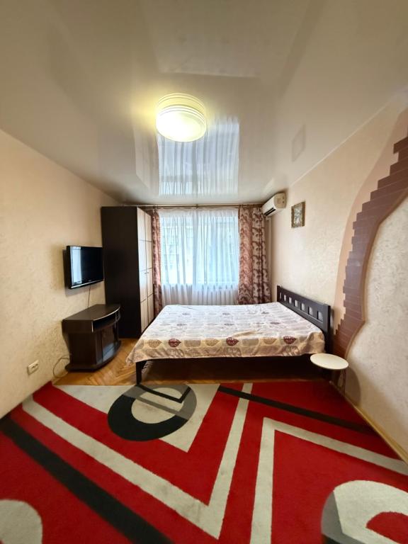 Schlafzimmer mit einem Bett und einem roten und weißen Teppich in der Unterkunft 31 m City Center Apartment for 3 Near Central Market 1К у центрі, 31 м , біля Центрального ринку in Mykolajiw
