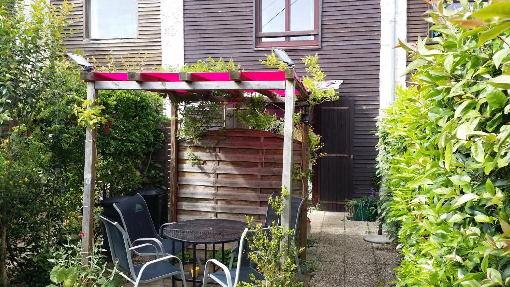 een pergola met een tafel en stoelen in een tuin bij Duplex14h 1er étage jardinet 1 parking ou studio14B rdc terrasse sans parking in La Rochelle