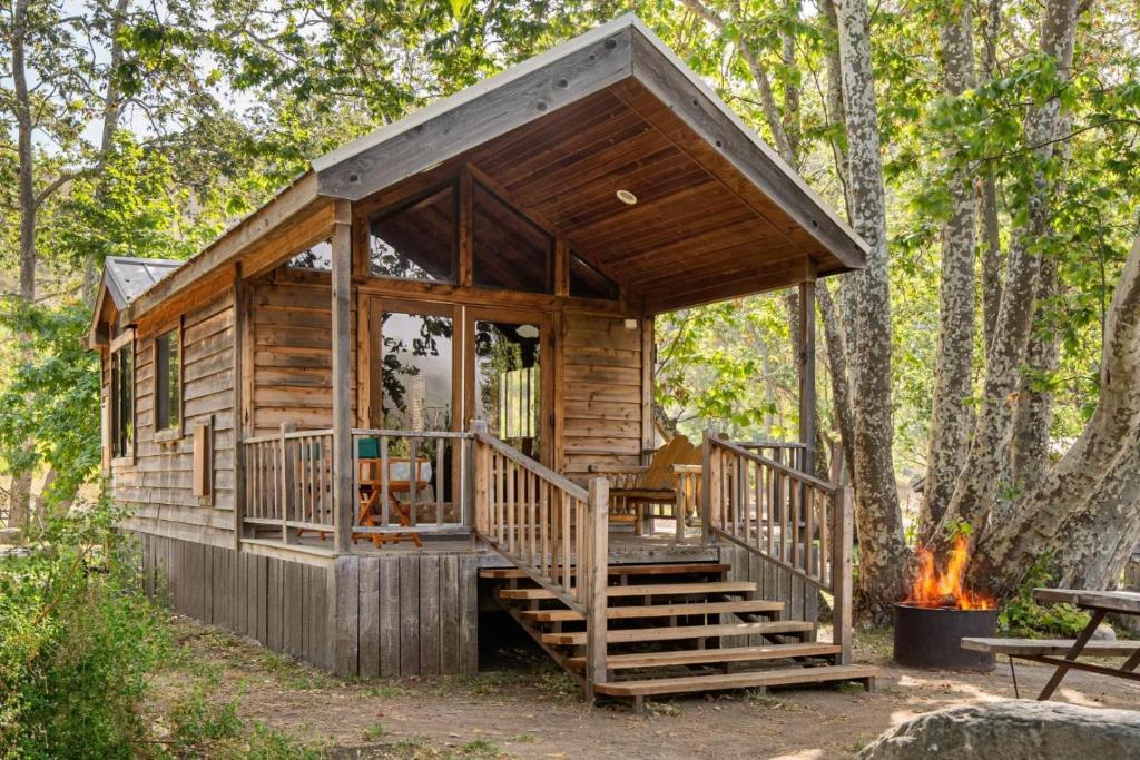 a log cabin in the woods with a fire at El Capitan Canyon in Capitan