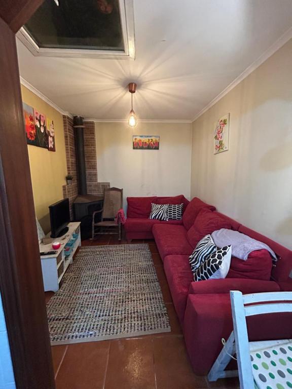 een woonkamer met een rode bank bij Casinha de chocolate in Outeiro