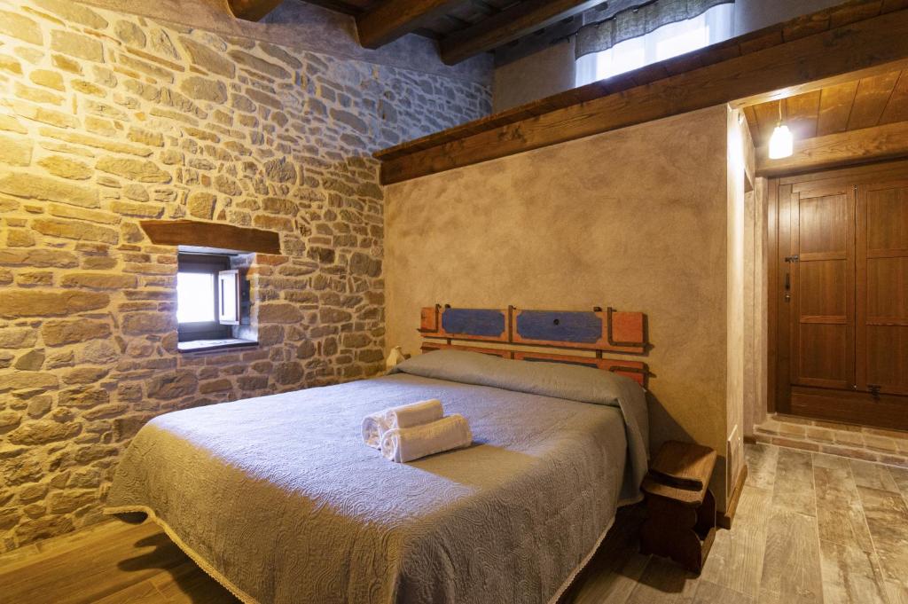 Un dormitorio con una cama en una pared de piedra. en Borgofortino, en Rovitolo