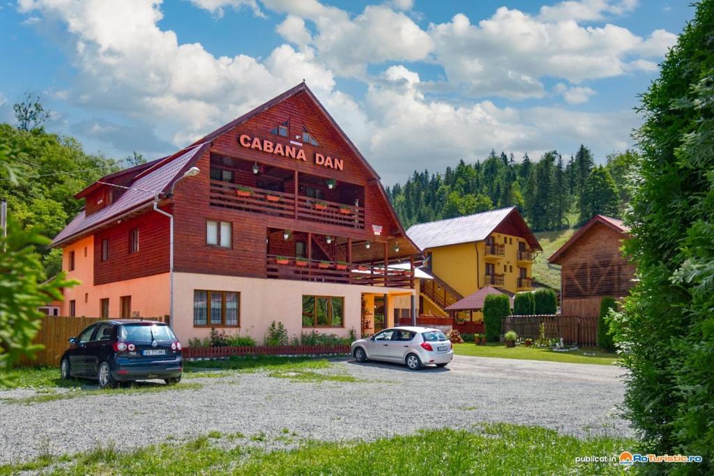 a building with two cars parked in front of it at Cabana Dan Arieseni in Arieşeni