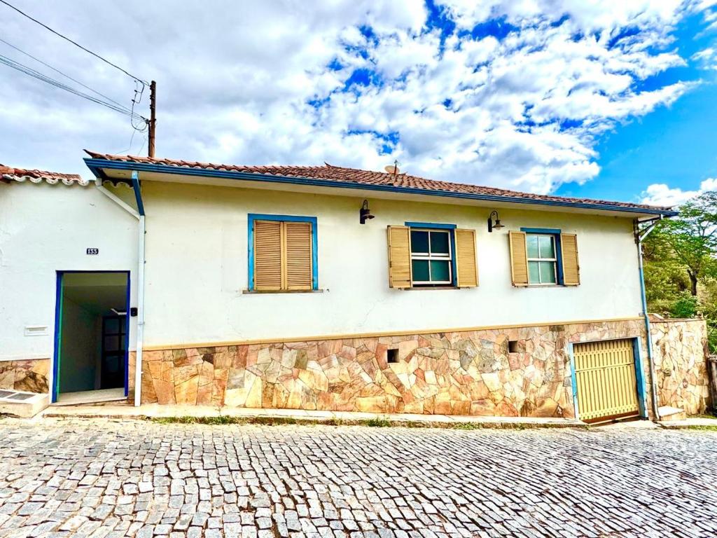 a white house with a stone wall at Casa Charmosa no Centro Histórico in Ouro Preto