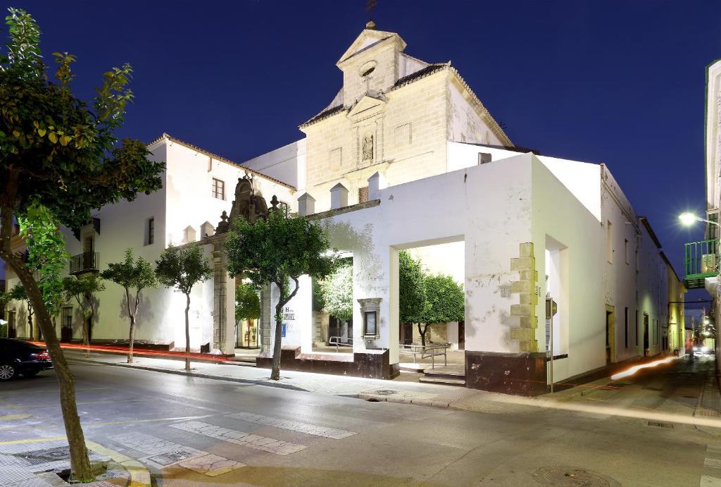 a large white building with a tower on a street at Crisol Monasterio de San Miguel in El Puerto de Santa María