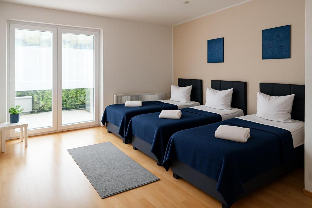 a bedroom with three beds with blue sheets and a window at SUNNYHOME Monteurwohnungen und Apartments in Weiden in Moosbürg