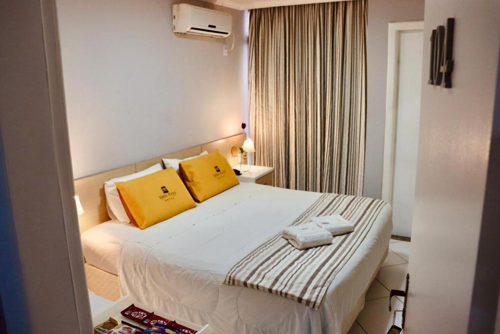 a bedroom with a large bed with yellow pillows at Serra Plaza Hotel in Serrinha