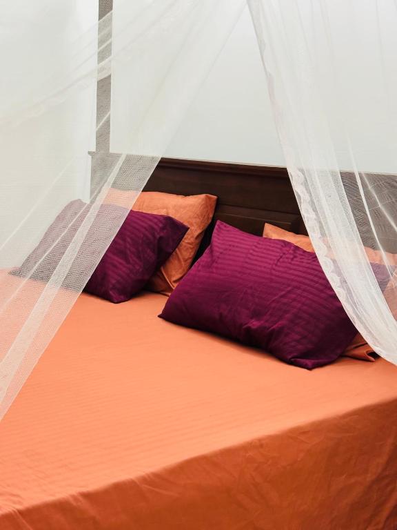 a bed with two purple pillows and a curtain at The Pearl Heaven in Dickwella