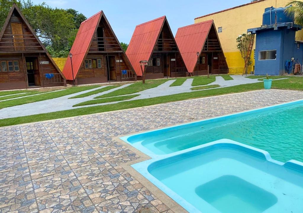 a swimming pool in front of a building at Chalé Lemes in Anchieta
