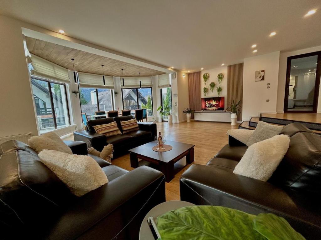 Una sala de estar con sofás de cuero y una mesa. en Zafra Chalet, en Poiana Ţapului