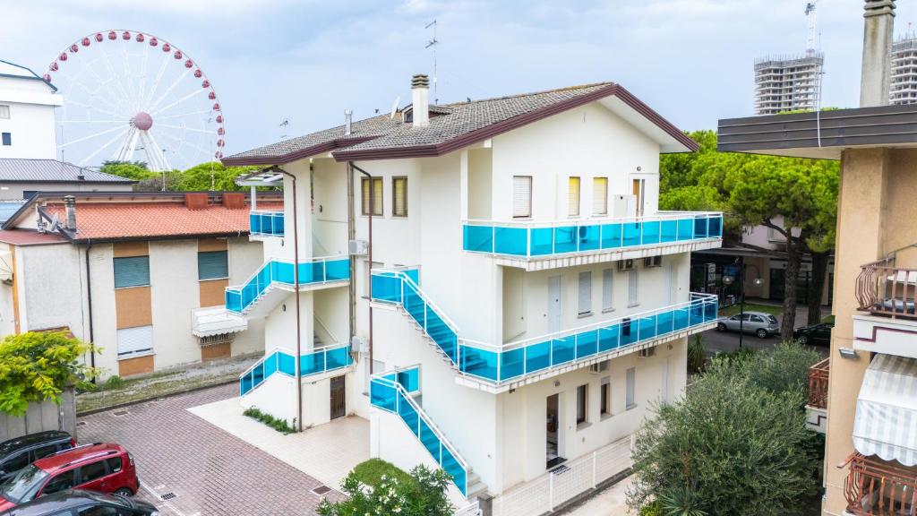 an apartment building with blue balconies and a ferris wheel at Appartamenti Casa De Lazzari - Piazza Brescia - Adria Holiday Jesolo - FAMILY APARTMENTS in Lido di Jesolo