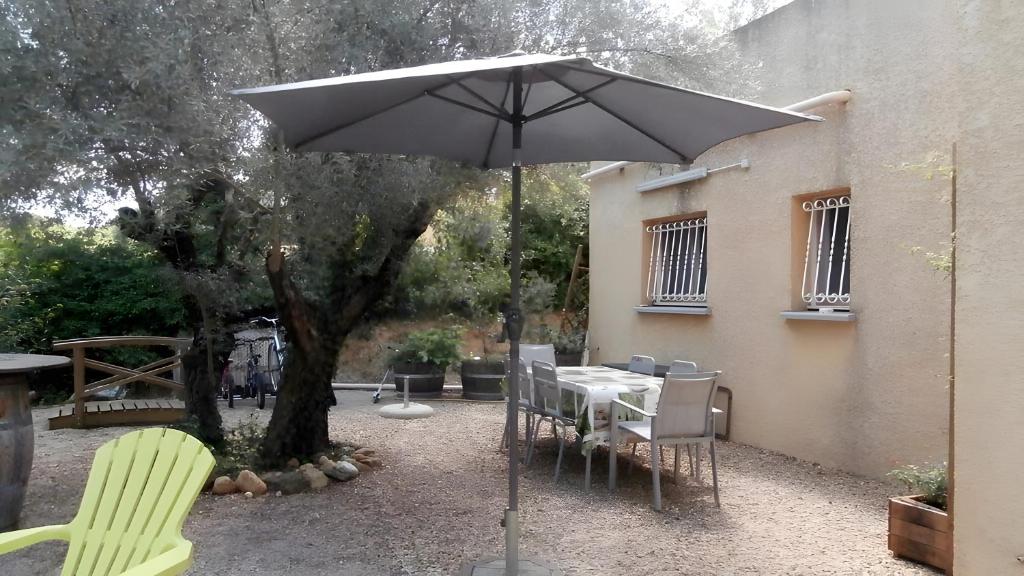 a table and chairs under an umbrella next to a tree at La Colline des Pins in Aniane