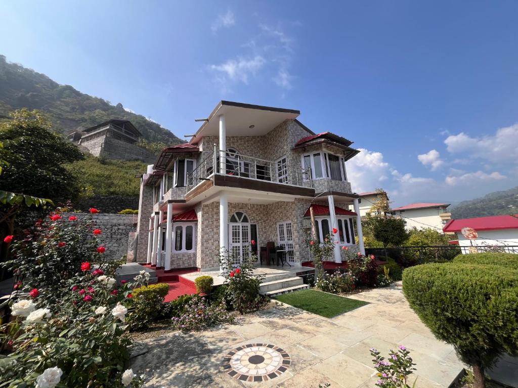 Una casa grande con flores delante de ella. en RaahgirStays The Lake Nest, en Bhimtal