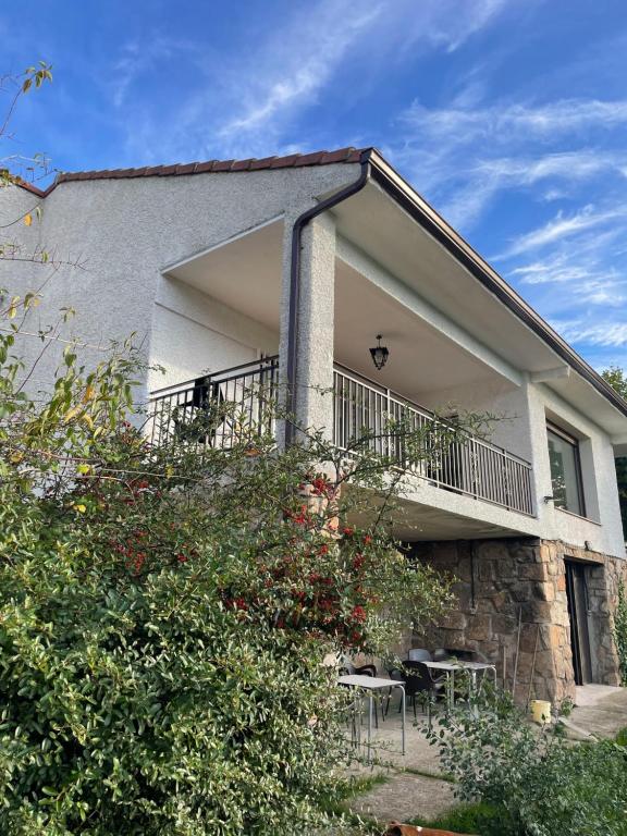 a building with a balcony with tables and chairs at Villa Pastora in Garganta de los Montes