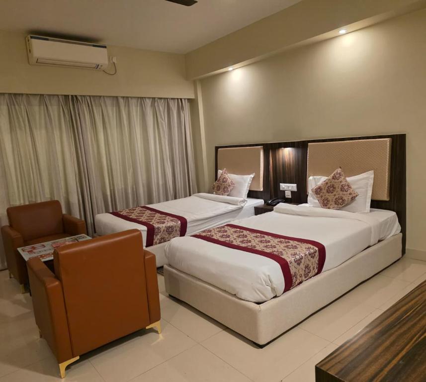 a hotel room with two beds and a chair at Hotel Star Bodh Gaya in Bodh Gaya