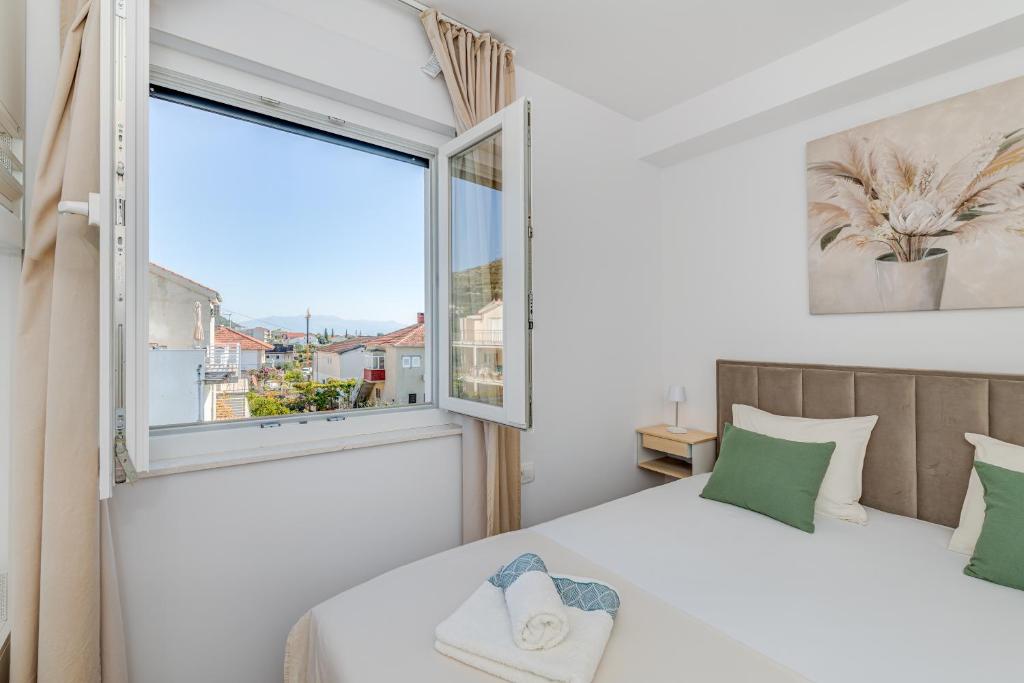 een slaapkamer met een bed en een groot raam bij Apartmani Zaja in Trogir