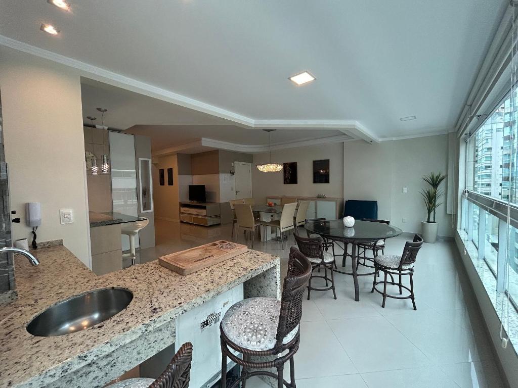 a kitchen and dining room with a table and chairs at Apto Almeida e Moraes 3 Suítes com churrasqueira Meia Praia in Meia Praia