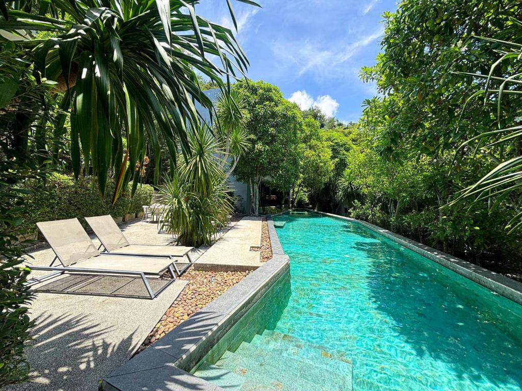 une piscine avec deux chaises longues à côté dans l'établissement Design Duplex Pavillion 2 BR Natural Park P11, à Kamala Beach