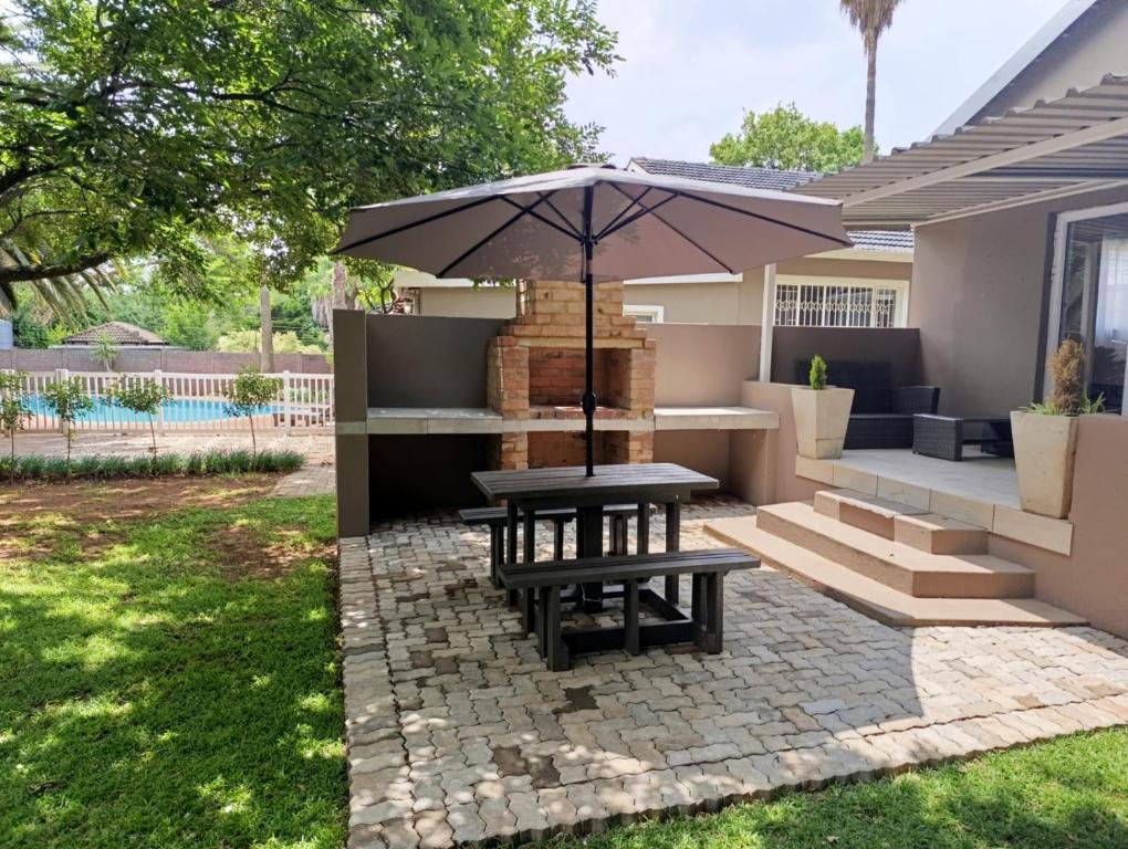 a picnic table with an umbrella on a patio at Joy Haven - Cottage in Centurion
