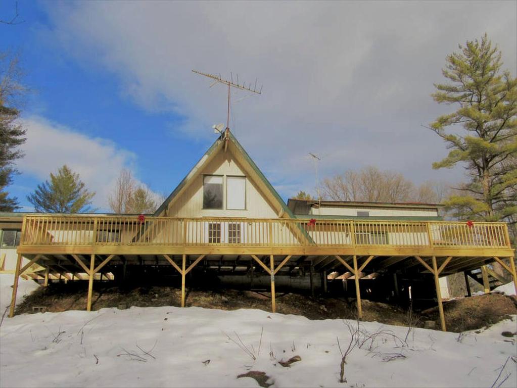a house with a large deck in the snow at Charming Cabin Retreat in the Foothills of the Adirondacks in Fort Ann, New York in Fort Ann